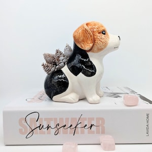 May include: Ceramic planter shaped like a beagle dog, with brown, black and white markings. The planter is sitting on a book with the text "Saltseeker" printed on the cover.