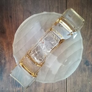 Könnte beinhalten: Eine klare Glasschüssel mit einem wellenförmigen Design und einem dekorativen Griff. Der Griff ist aus bernsteinfarbenem Glas und hat ein Blumenmuster.