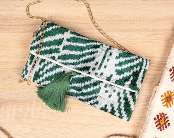 Clutch artesanal em veludo verde esmeralda com estampa ikat, modelo moderno e geométrico com franjas.