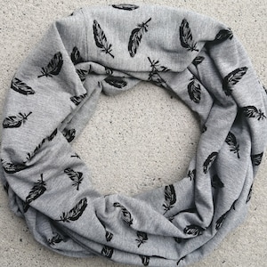 May include: Grey infinity scarf with a black feather print.