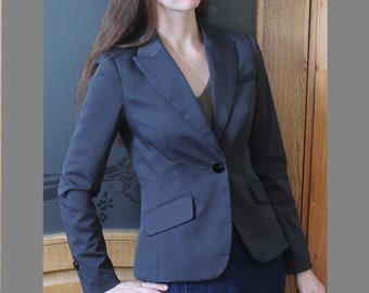 May include: A woman wearing a dark gray blazer with a single button closure and a dark blue denim skirt.