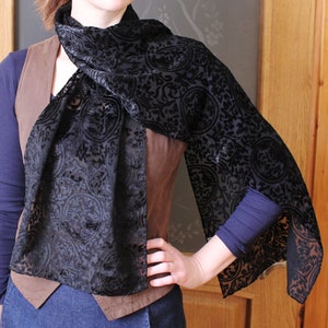 May include: A black sheer scarf with a floral pattern. The scarf is made of a soft, lightweight fabric and has a delicate, feminine feel.