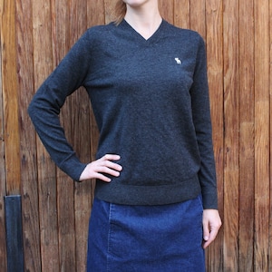 May include: A dark gray long-sleeved v-neck sweater with a small white logo of a horse on the chest.