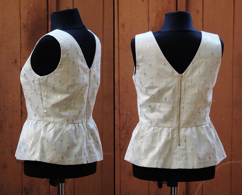 May include: A white sleeveless top with a gold pattern and a zipper down the back. The top has a peplum hemline.