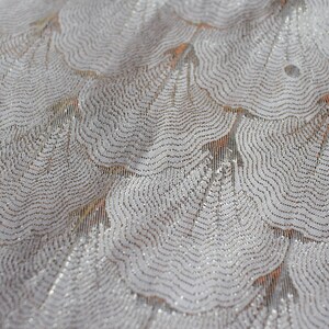 May include: White fabric with a silver glitter pattern of overlapping, wavy circles.