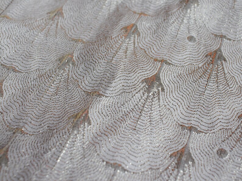 May include: White fabric with a silver glitter pattern of overlapping, wavy circles.
