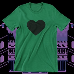 Puede incluir: Una camiseta verde con un gráfico de corazón negro en la parte delantera.