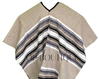 May include: A beige poncho with black, white, and gray stripes. The poncho has fringe on the bottom.