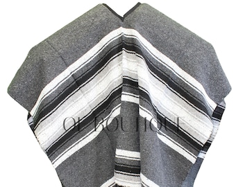 May include: A gray and black striped poncho with white stripes and fringe on the bottom.