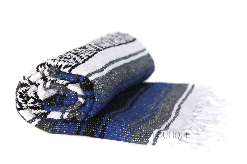 May include: A rolled up blue, white, black, and gray striped Mexican blanket with white fringe.