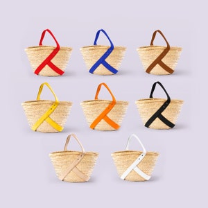 Peut inclure: Ensemble de dix sacs cabas en paille avec des anses en cuir et des sangles colorées. Les sacs sont disposés en deux rangées de cinq, chaque rangée présentant une sangle de couleur différente : rouge, bleu, marron, jaune, orange, noir, beige, blanc et deux sacs beiges.
