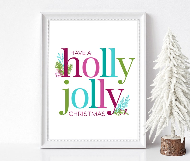 Może przedstawiać: Biały wydruk w ramie z tekstem "Have a holly jolly Christmas" w kolorowych literach z zielonymi, niebieskimi, r&oacute;żowymi i czerwonymi liśćmi i jagodami ostrokrzewu.