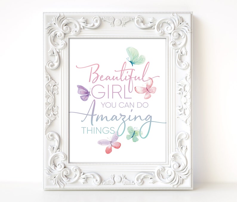 May include: A framed print with the words "Beautiful Girl You Can Do Amazing Things" in a script font. The print features watercolor butterflies in shades of pink, purple, and teal. The frame is white with ornate detailing.