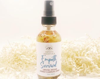 Puede incluir: Una botella de vidrio transparente con un pulverizador negro llena de un líquido amarillo y pétalos de flores secas. La etiqueta dice "Empath Essentials Empath Survival Crystal Infused Energy Cleansing Spray 2 oz | 60 ml".