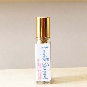 May include: A clear glass roller bottle with a gold lid and a white label that reads "Empath Survival Crystal Infused Energy Cleansing Oil".