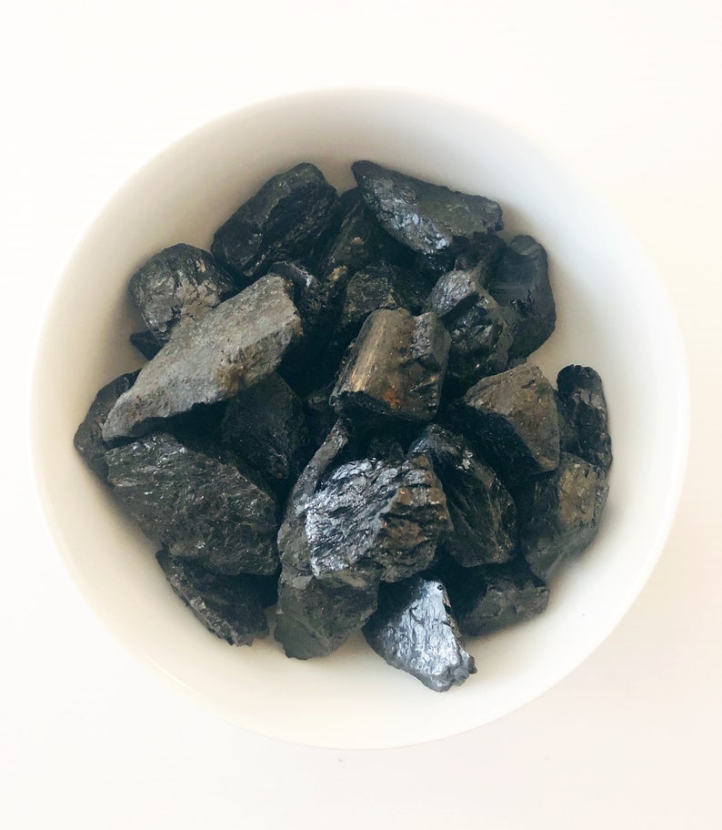 May include: A white bowl filled with black charcoal pieces.