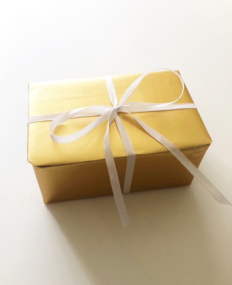 May include: A gold gift box with a white satin ribbon tied in a bow.