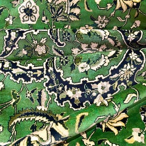 May include: A green rug with a floral pattern. The rug has a traditional Persian design with intricate details and a variety of colors, including white, black, and cream.