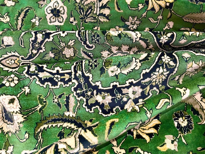 May include: A green rug with a floral pattern. The rug has a traditional Persian design with intricate details and a variety of colors, including white, black, and cream.