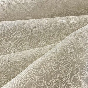 May include: White fabric with an embossed paisley pattern. The fabric has a soft, textured surface.