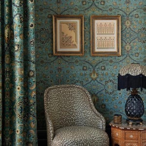 May include: A teal blue patterned wallpaper with a leopard print chair, two framed prints, and a black pineapple lamp with a black fringe lampshade.