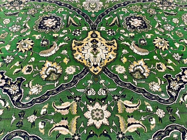May include: A green rug with a floral pattern in shades of white, yellow, and black. The rug has a symmetrical design with a central motif.