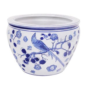 May include: A white ceramic planter with a blue and white bird and floral design. The planter features a detailed illustration of a bird perched on a branch with flowers and foliage. The rim has a decorative border.