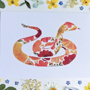 May include: A greeting card featuring a snake made of pressed flowers. The snake is coiled and has a red, orange, and yellow color scheme.
