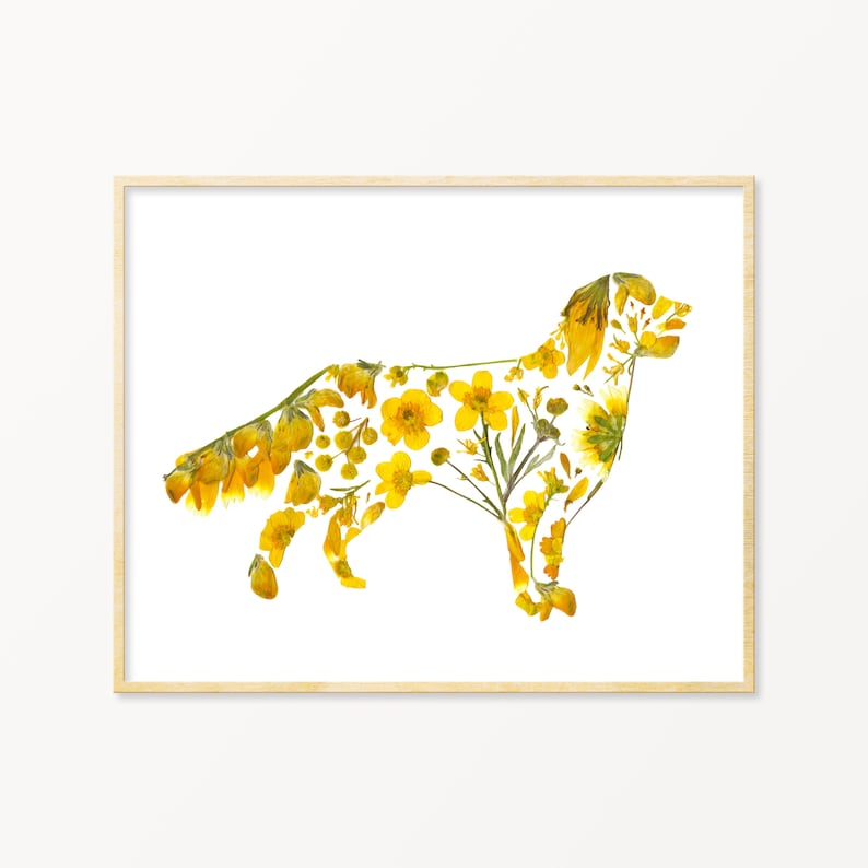 May include: A framed print featuring a dog silhouette filled with yellow flowers and greenery. The artwork is set against a white background, with a light-colored wooden frame. The floral arrangement creates a unique and naturalistic design.