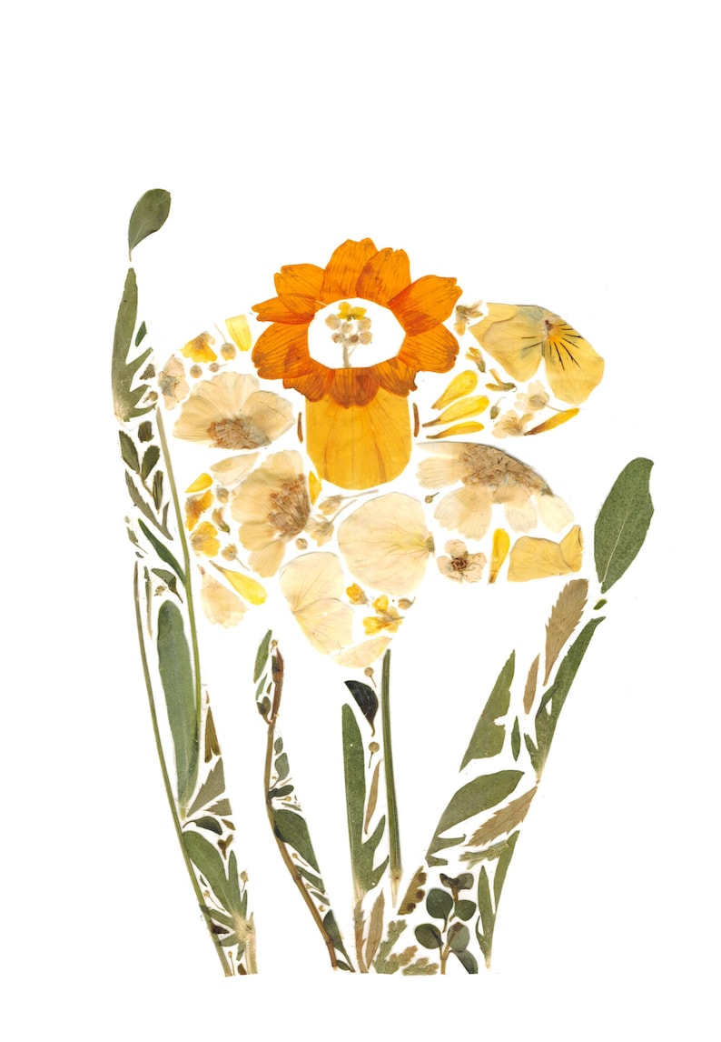 May include: A yellow and orange flower made from pressed flowers and leaves. The flower is a daffodil with a large, orange center and a white trumpet. The flower is surrounded by green leaves.