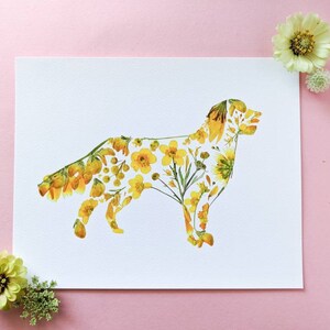 May include: A white print featuring a dog silhouette filled with yellow flowers and greenery. The artwork is surrounded by yellow flowers and greenery on a pink background. A unique floral art piece.