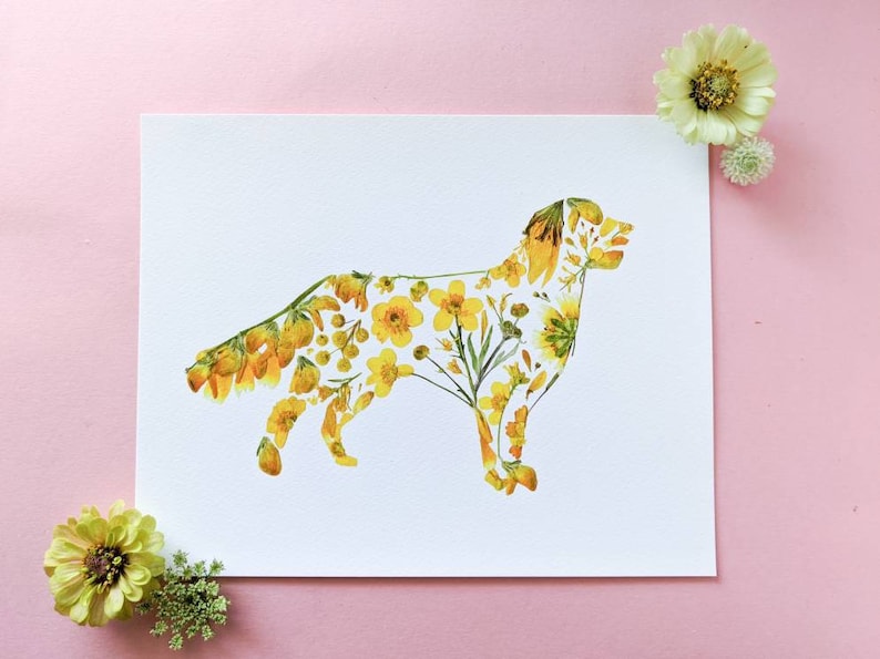 May include: A white print featuring a dog silhouette filled with yellow flowers and greenery. The artwork is surrounded by yellow flowers and greenery on a pink background. A unique floral art piece.