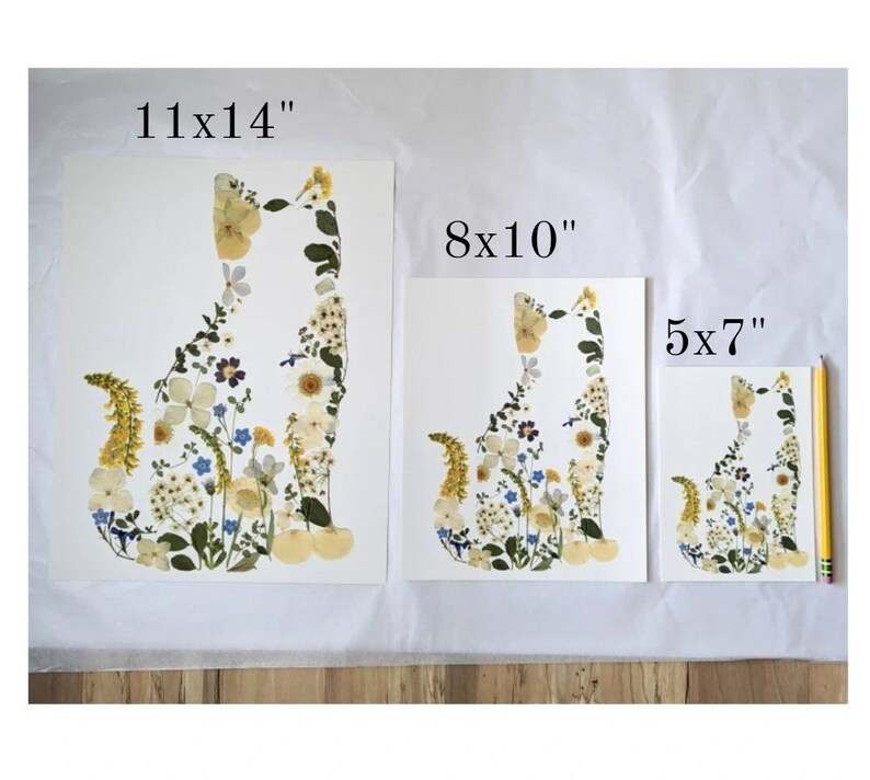 May include: Three framed art prints featuring a cat silhouette composed of dried flowers. The largest print is 11x14 inches, the middle is 8x10 inches, and the smallest is 5x7 inches. The flowers are in shades of yellow, white, blue, and green.
