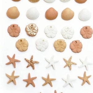 May include: Assortment of seashell and starfish charms in various colors, including white, gold, and brown. The charms are made of different materials, including glitter, wood, and plastic.