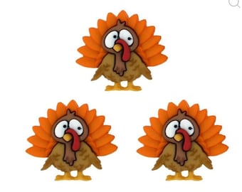 May include: Three orange and brown cartoon turkey buttons with white eyes and red beaks.