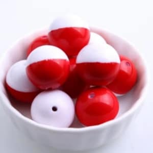 May include: A bowl of red and white half-round beads. The beads are made of plastic and have a glossy finish.
