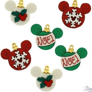 Puede incluir: Seis adornos navideños con forma de orejas de Mickey Mouse. Los adornos son rojos, verdes y blancos con diferentes diseños, incluyendo acebo, copos de nieve y la palabra "Noël".
