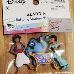 May include: A package of Disney Aladdin buttons featuring Aladdin, Genie, and Jasmine. The package includes a warning about small parts and is made in the USA. The buttons are colorful and detailed.