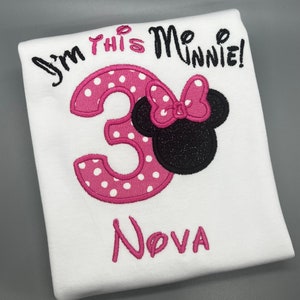 May include: White t-shirt with pink and white polka dot number 3, a black and pink Minnie Mouse head, and the text "I'm this Minnie!" and "Nova" in pink.