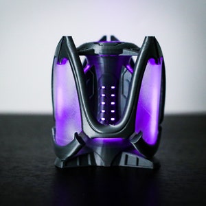 May include: A black 3D printed object with a purple glow. The object has a geometric design with a central column and multiple arms.