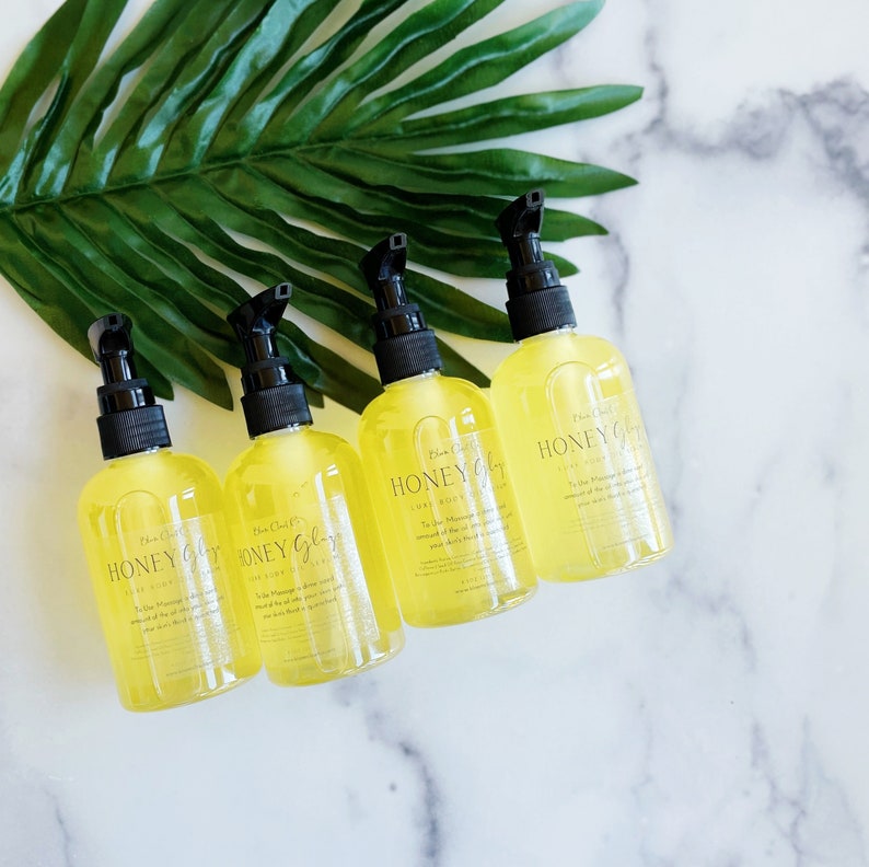 Pu&ograve; includere: Quattro bottiglie di vetro ambrato con pompe nere riempite di un liquido giallo. Le bottiglie sono etichettate "Honey Glow" e "Lux Body Oil".