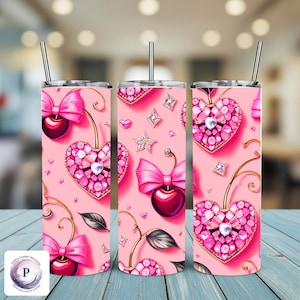 May include: Pink tumbler with a cherry and bow design. The tumbler features a cherry with a pink bow, a heart-shaped design with pink gems, and a silver straw. The design includes hearts, stars, and leaves.