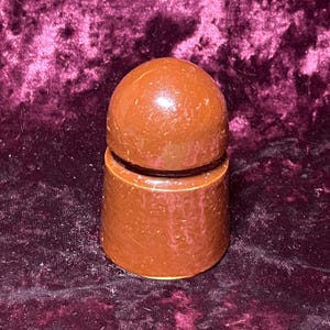 May include: A brown bottle stopper with a rounded top and cylindrical base. The stopper is made of a glossy material and has a smooth, polished appearance. The design is simple and elegant, suitable for various bottle types.