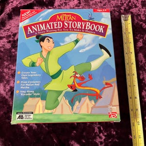 May include: A box for a Disney's Mulan Animated Storybook computer game. The box features a colourful illustration of Mulan in a green and yellow outfit, running with Mushu the dragon. The text on the box reads "Disney's Mulan Animated Storybook. A Story Waiting For You To Make It Happen."
