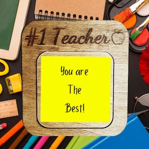 Może przedstawiać: Drewniana ramka z tekstem "#1 Teacher" i czerwonym jabłkiem. Żółta karteczka samoprzylepna wewnątrz ramki głosi "You are The Best!"