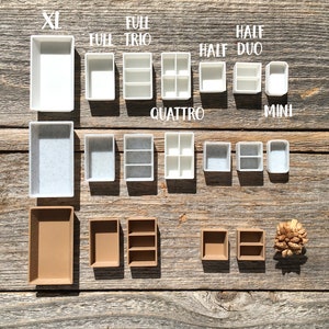 Może przedstawiać: Zestaw białych i brązowych plastikowych pojemnik&oacute;w do przechowywania w r&oacute;żnych rozmiarach. Pojemniki są oznaczone rozmiarami "XL", "Full", "Trio", "Quattro", "Half", "Duo" i "Mini".