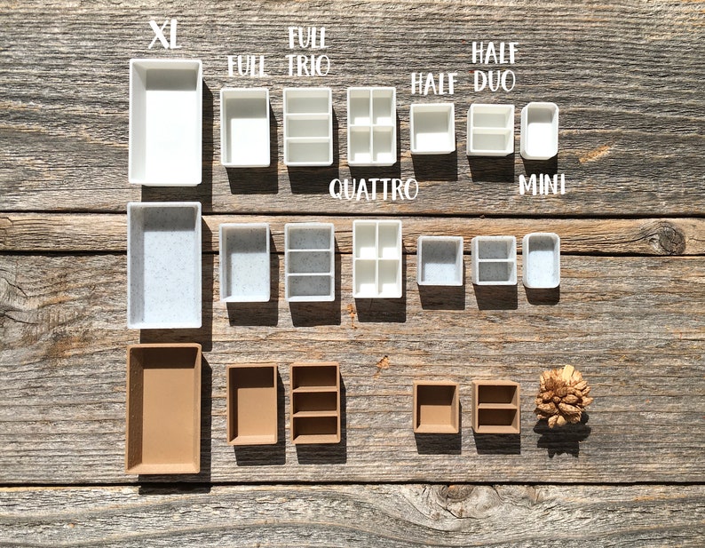 Może przedstawiać: Zestaw białych i brązowych plastikowych pojemnik&oacute;w do przechowywania w r&oacute;żnych rozmiarach. Pojemniki są oznaczone rozmiarami "XL", "Full", "Trio", "Quattro", "Half", "Duo" i "Mini".