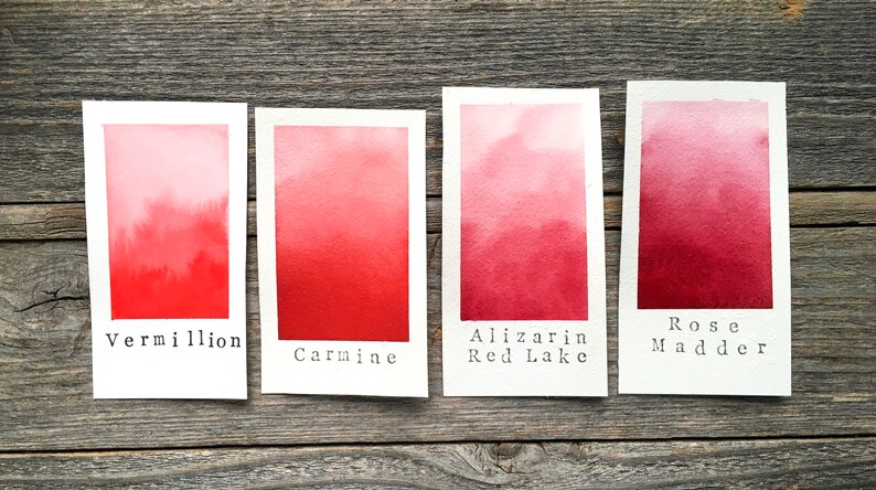 Op de afbeelding: Vier aquarelverfstaaltjes op witte kaartjes, die een verloop van licht naar donker laten zien. De staaltjes zijn gelabeld met "Vermiljoen", "Karmijn", "Alizarinroodmeer" en "Rozenmadder".