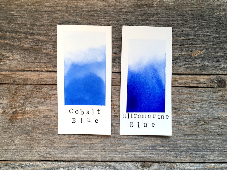 May include: Two watercolor swatches on white cardstock, one labeled "Cobalt Blue" and the other "Ultramarine Blue". The swatches show a gradient from light to dark blue.