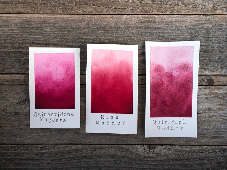Op de afbeelding: Drie aquarelverfstaaltjes op wit papier, met de labels "Quinacridone Magenta", "Rose Madder" en "Quin. Pink Madder".